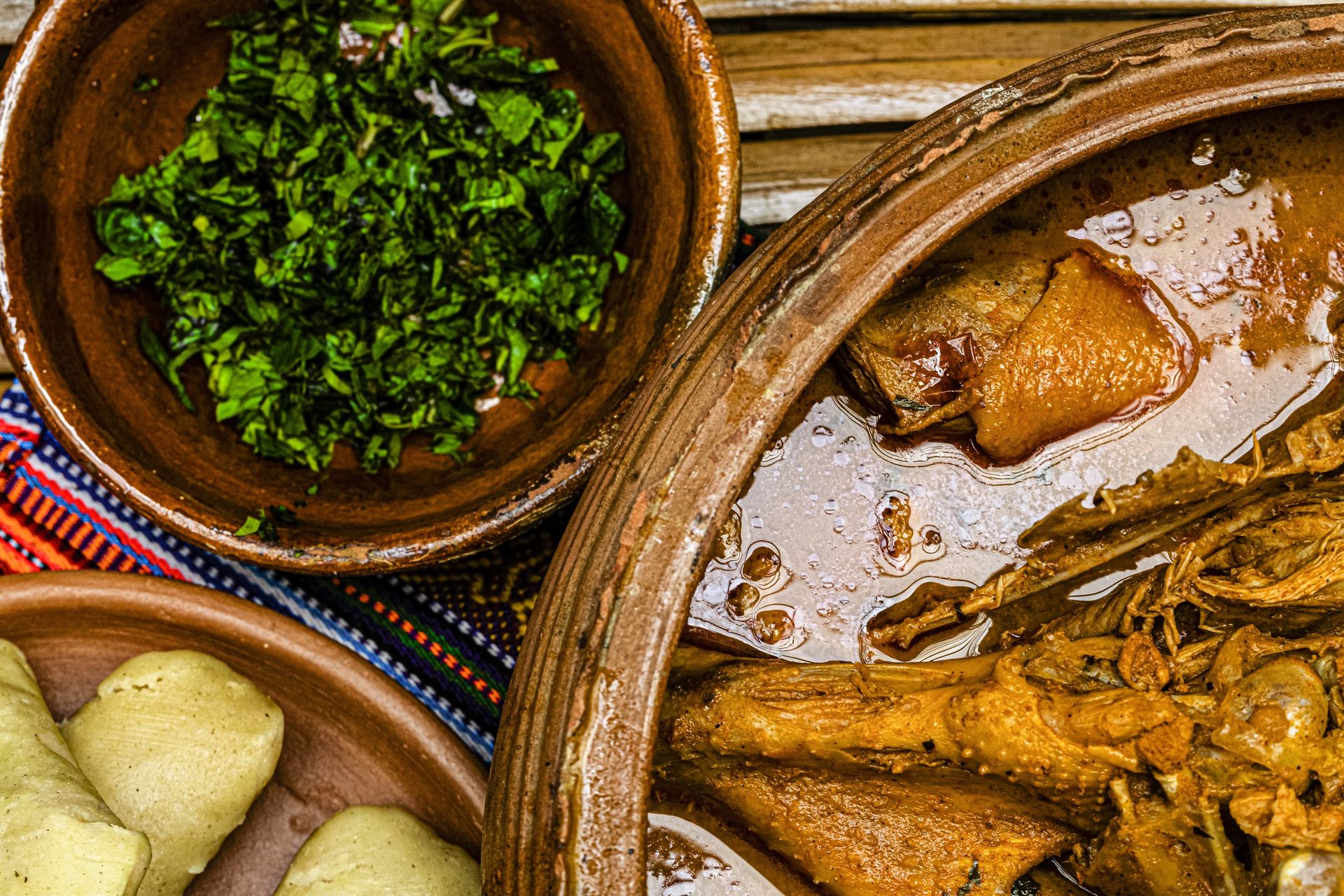 Traditional Kaq’ik in a clay pot with tamales and a bowl of green recado